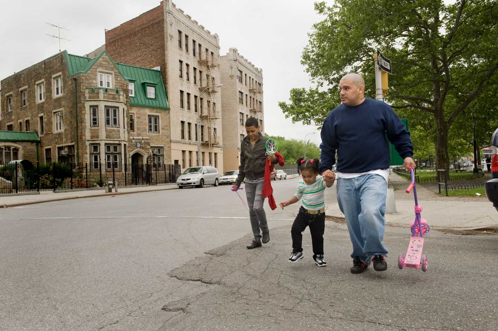 A family walking on a city road and holding hands.