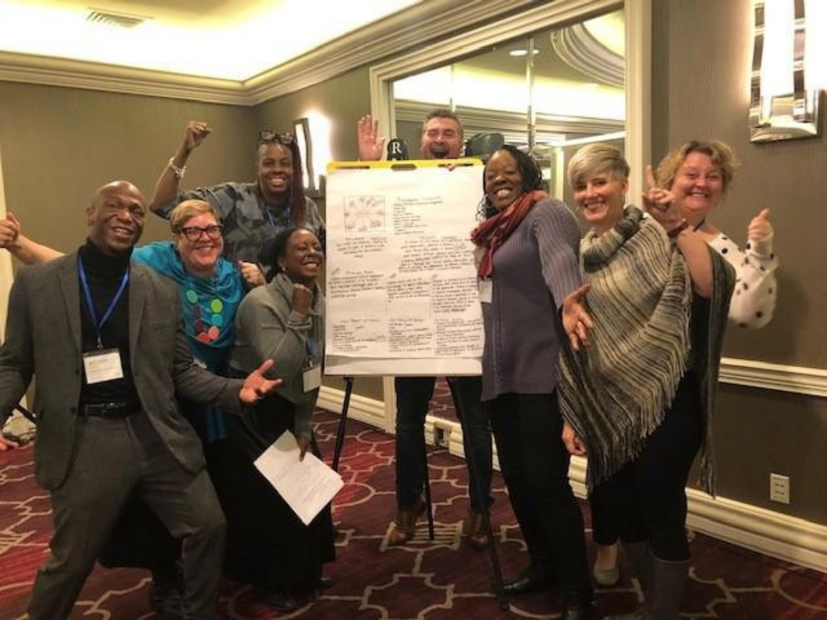 People Gathered Around Board for Race Equity Design Challenge