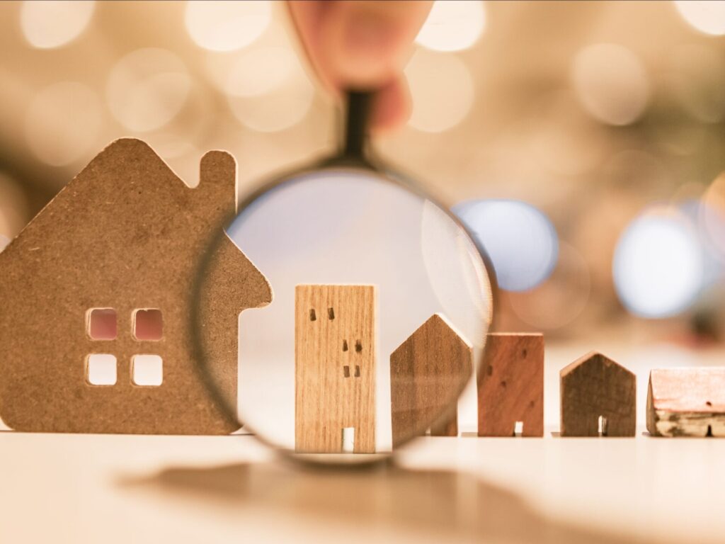 This is an image of wooden houses and buildings with a magnifying glass highlighting a residential building
