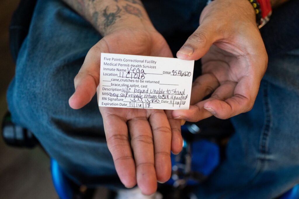 Jose Vega holding his correctional facility medical permit, which has a description of his disability